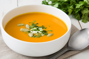 Pumpkin soup in bowl on a white wooden table

