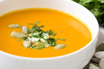 Pumpkin soup in bowl on a white wooden table

