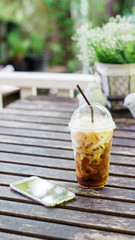 Iced coffee and smartphone on the wood table.