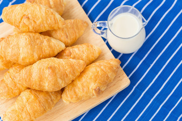 fresh croissants with milk on wooden table