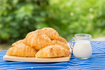 fresh croissants with milk on wooden table