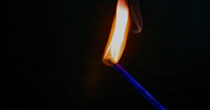 There is a big fire on a blue match and then is suddenly starts diminishing. Close-up shot.
