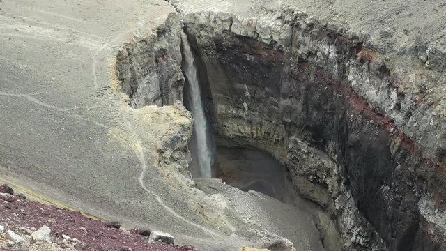 Muddy waterfall from crater of Mutnovsky volcano. Kamchatka, Russia.