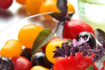 The decoration of the flowers of Basil on a cherry tomato salad with olives. close-up.