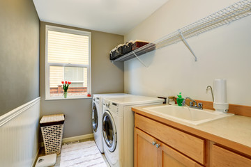 Laundry room with wood cabinets and tile floor.