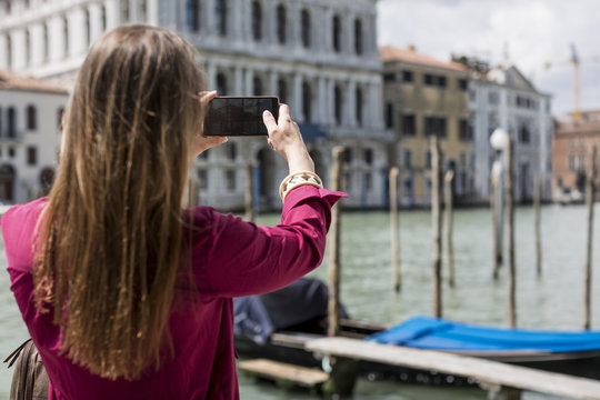 Italy, Venice, tourist taking pictures with smartphone