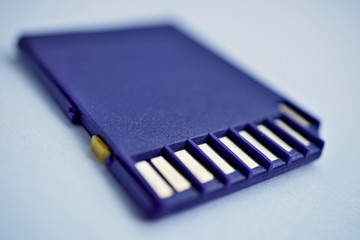 Isolated plastic compact memory card (SD card - Secure Digital card) used in cameras, computers and video cameras in a blue color with metal connectors in the golden color 