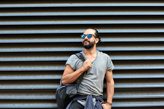 man with backpack standing at city street wall