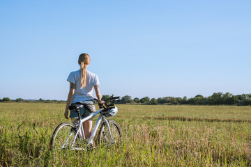Obraz premium young woman with bicycle walking in fields 