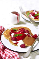 Pancakes with raspberry sauce and cream on a vintage plate.