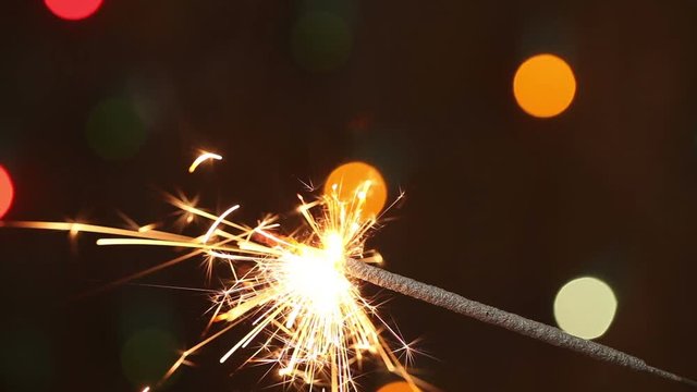 burning sparkler on background blinking blurred garland
