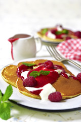 Pancakes with raspberry sauce and cream on a vintage plate.