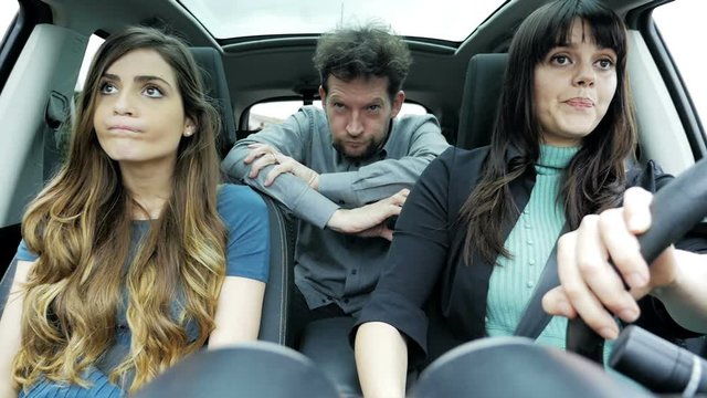 Two women one man in car making funny crazy faces slow motion
