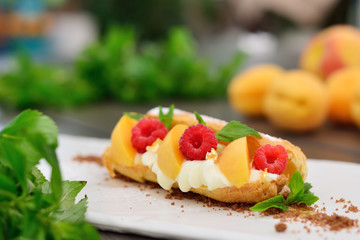 choux pastry with raspberry and apricot. Modern supply of gold a