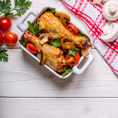 Chicken legs fried with mushrooms and tomatoes.