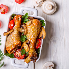 Chicken legs fried with mushrooms and tomatoes.
