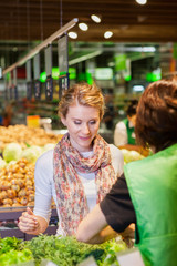 Portrait of beautiful young woman choosing green leafy vegetable