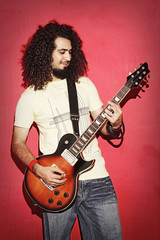 Obraz premium Passionate guitarist happy with beautiful long curly hair playin