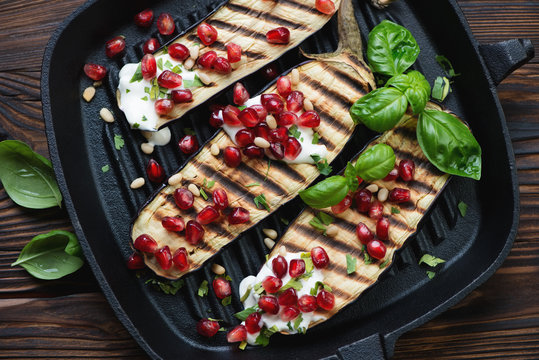 Grill pan with roasted aubergine slices, pomegranate, sour cream