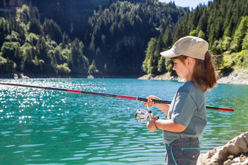 giovane bambina che pesca in un laghetto in montagna - obrazy, fototapety, plakaty
