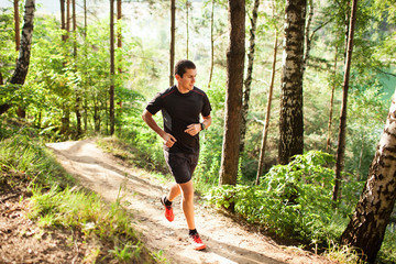 Naklejka na ściany i meble Male athlete runner running on road in forest