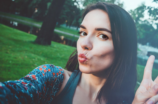 Pretty girl taking photo selfie and making duck face. Female sending kisses, enjoying self portrait. Herself Instagram concept. Lifestyle of happy woman looking on camera phone.
