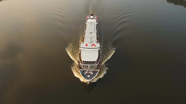 Aerial view.Large white cruise ship on a river.Cruise ship sailing along the river among the green forest and blue sky.Cruise ship on the river through the green trees and forest.4K video,ultra HD