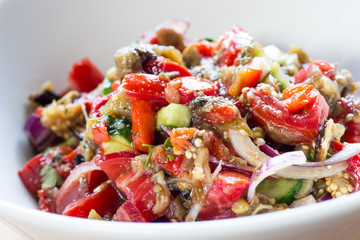 Baked vegetables salad in white bowl.