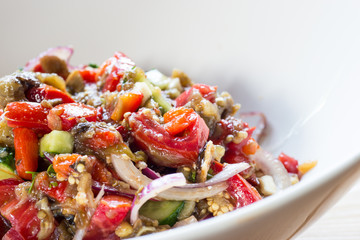 Baked vegetables salad in white bowl.