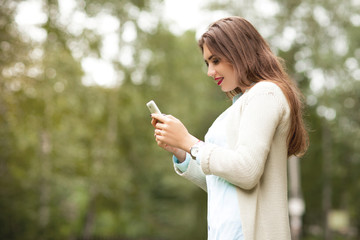  Beautiful girl in a white jacket looks at the phone screen and