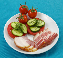 Ломтики бекона с помидорами и огурцами на голубом фоне