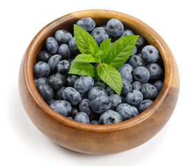 Свежая голубика с зелеными листочками мяты в деревянной миске