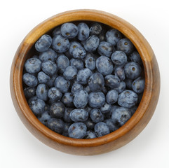 Свежая голубика  в деревянной миске на белом фоне