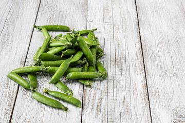 green peas pods on a white wooden table
