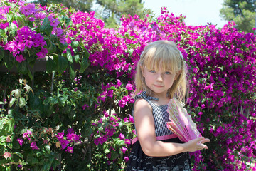 young girl with fan in front of bougainvillea flowers