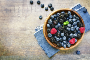Forest berries (blueberry,bramble) in a wooden bowl.Top view.