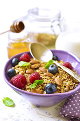 Homemade granola with fresh berry for a breakfast in a purple bo