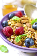 Homemade granola with fresh berry for a breakfast in a purple bo