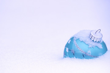 Teal blue Christmas ornament buried in snow