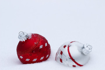 Red, white and silver Christmas ornaments buried in snow
 