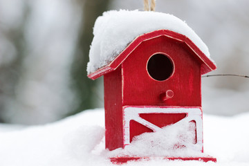 Fototapeta premium Red barn birdhouse covered in snow