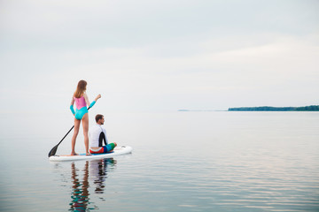 Young couple paddling on sup board