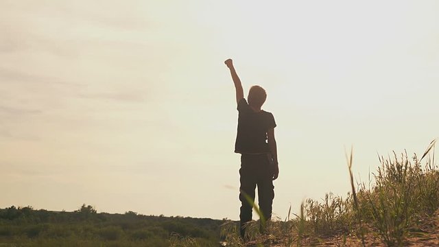 boy raises his hand up in a clearing superhero slow motion video