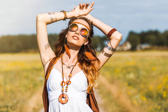 Pretty amazing free red-haired hippie girl dancing outdoors, feathers and braids in her hair, white dress, vest with fringe, accessories, sunglasses, tattoo flash, indie, Bohemian, boho style