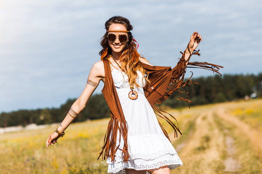 Pretty amazing free red-haired hippie girl dancing outdoors, feathers and braids in her hair, white dress, vest with fringe, accessories, sunglasses, tattoo flash, indie, Bohemian, boho style