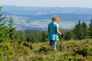 Dziewczynka z kijami trekingowymi podziwia górski krajobraz, w oddali Czorsztyn i dolina Dunajca 