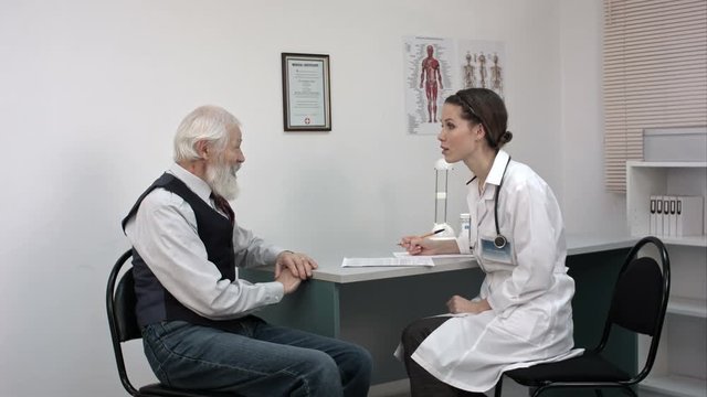 Doctor talking to senior man at her office.