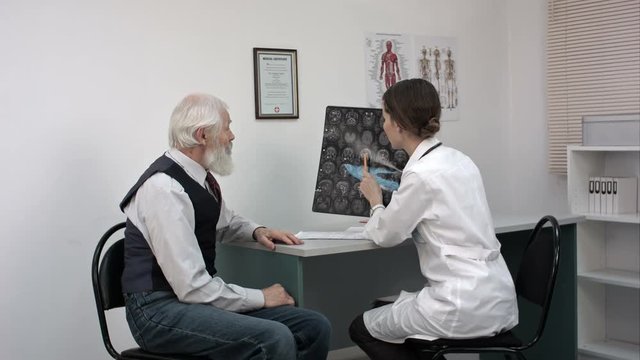 Doctor showing mri to the old patient and explaining something.