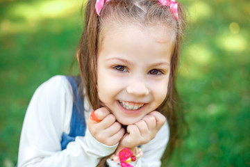 Sweet little girl outdoors with curly hair in two long tails, closeup portret.