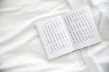 Opened book on white crumpled sheet